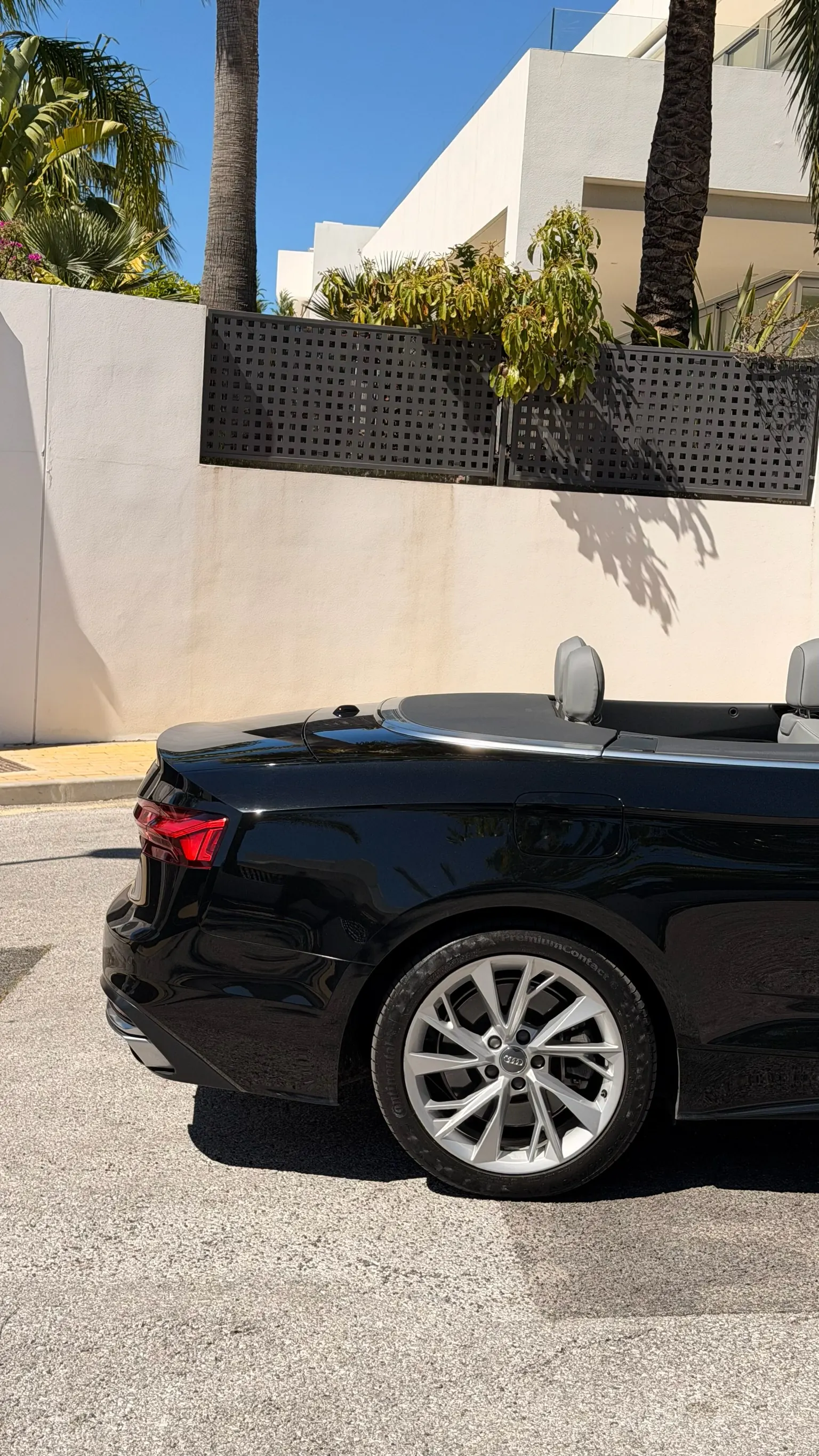 Detalle trasero del A5 Cabriolet con faro LED dinámico, llanta 5 radios y muro mediterráneo con palmeras