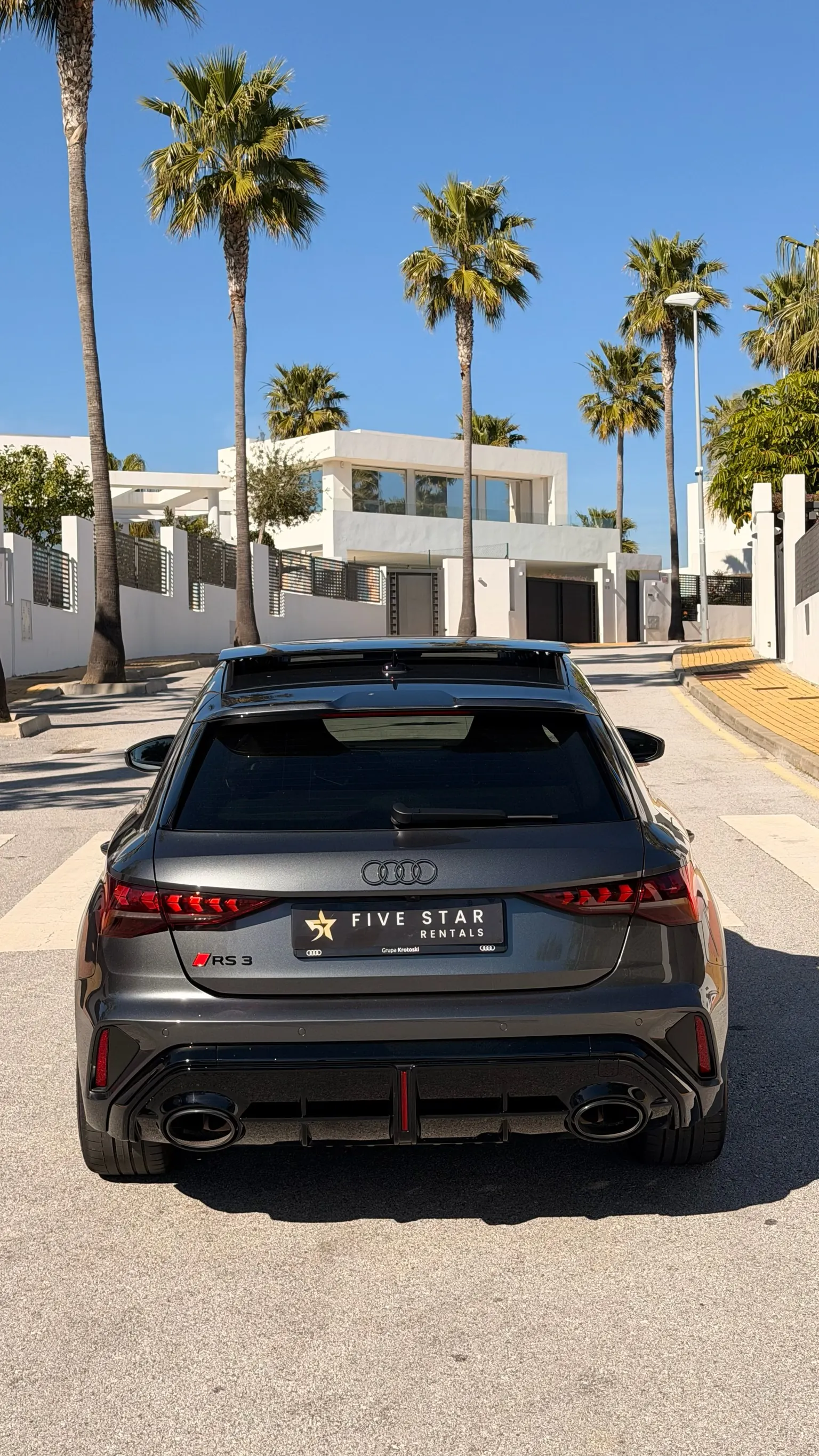 Centered rear view of the Audi RS3 Sportback with RS 3 badge, RS oval dual exhaust and black sport diffuser