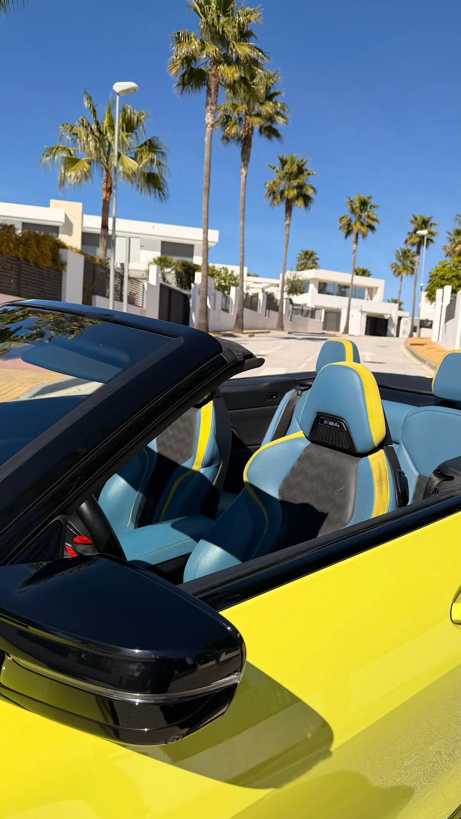 Vista cenital del interior de cuero azul y amarillo BMW Individual del M4 Cabriolet con fondo de Marbella
