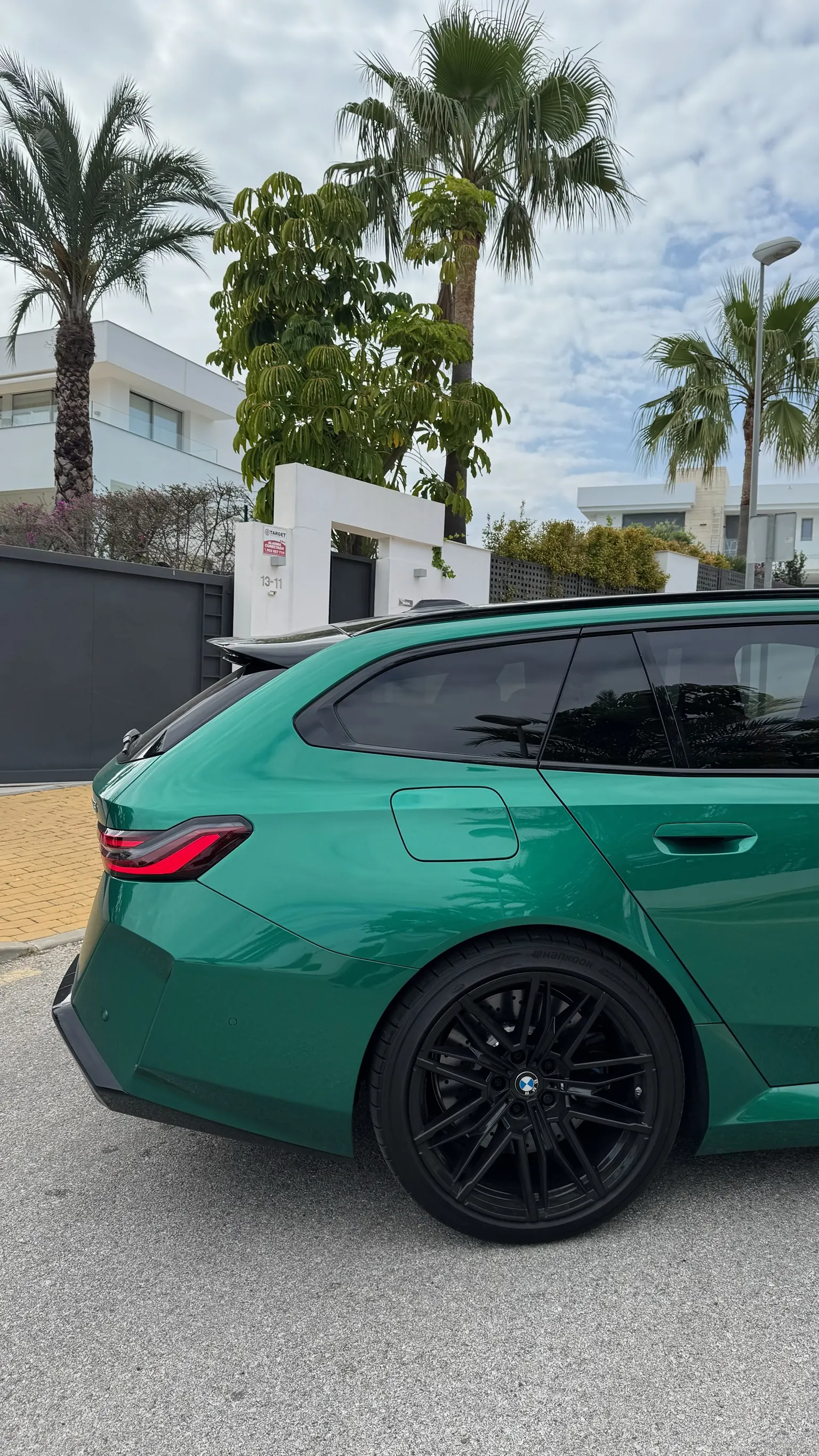 BMW M5 Touring rear three-quarter view with close-up M wheel and black roof spoiler