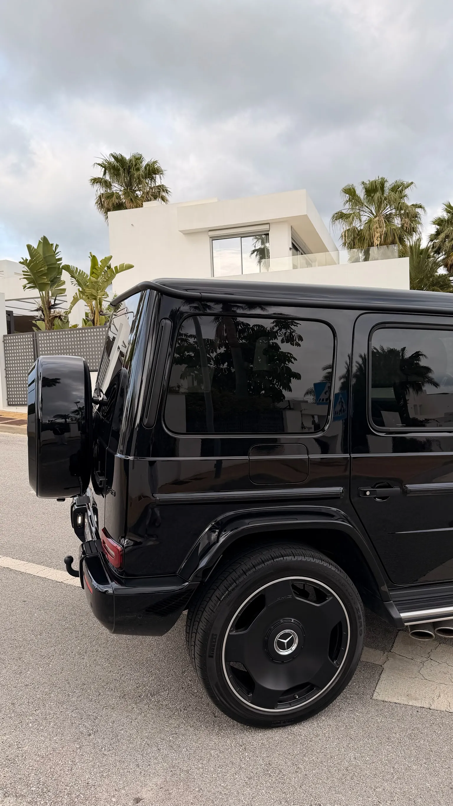 Rear three-quarter view of the black Mercedes-AMG G63 with body-coloured spare wheel cover, dark tinted windows and iconic Geländewagen silhouette