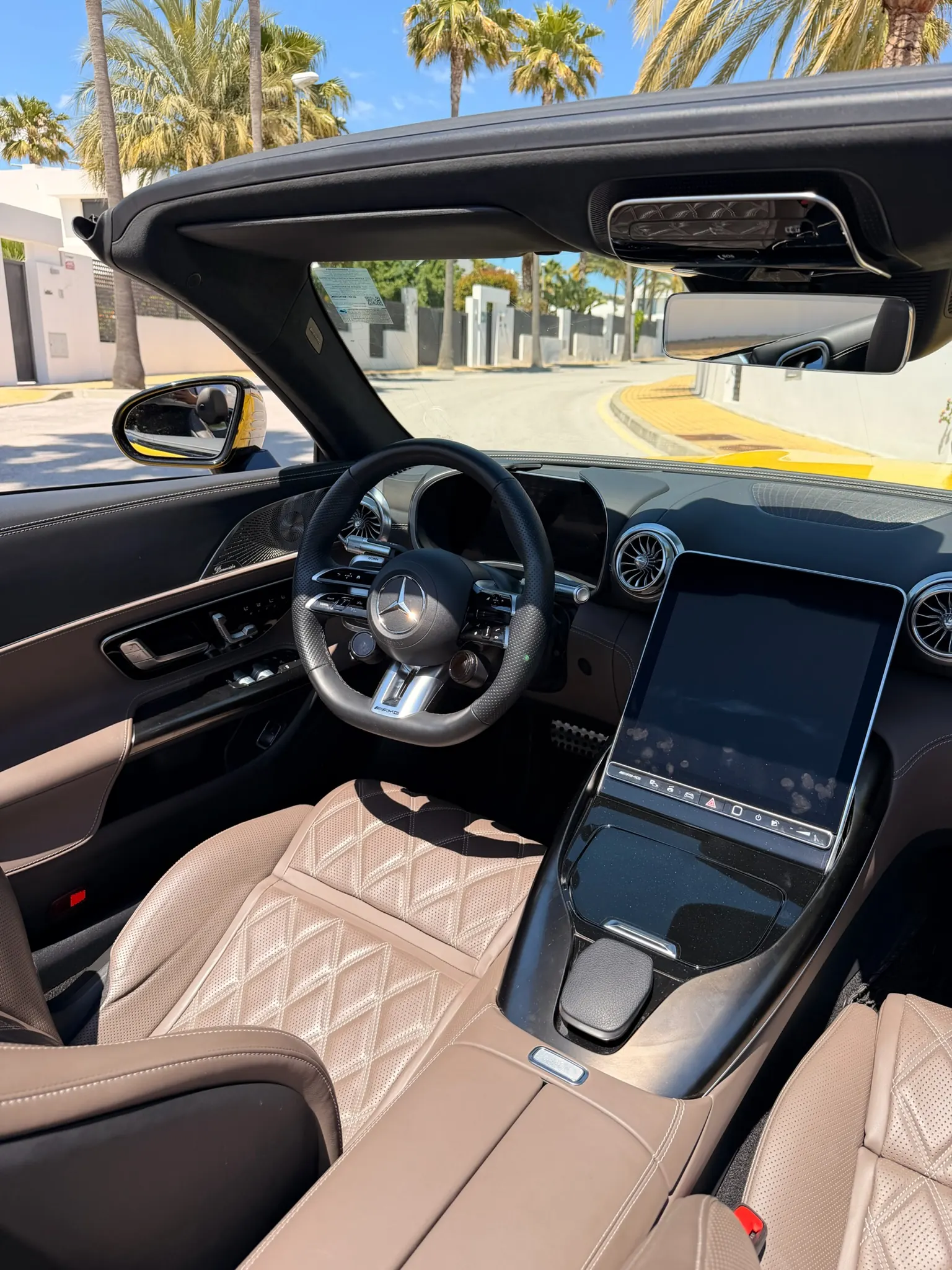 Cabina Mercedes-AMG SL 55 con pantalla MBUX vertical de 12,3 pulgadas inclinable, volante AMG en cuero perforado y asientos bicolor macchiato beige acolchados en rombos