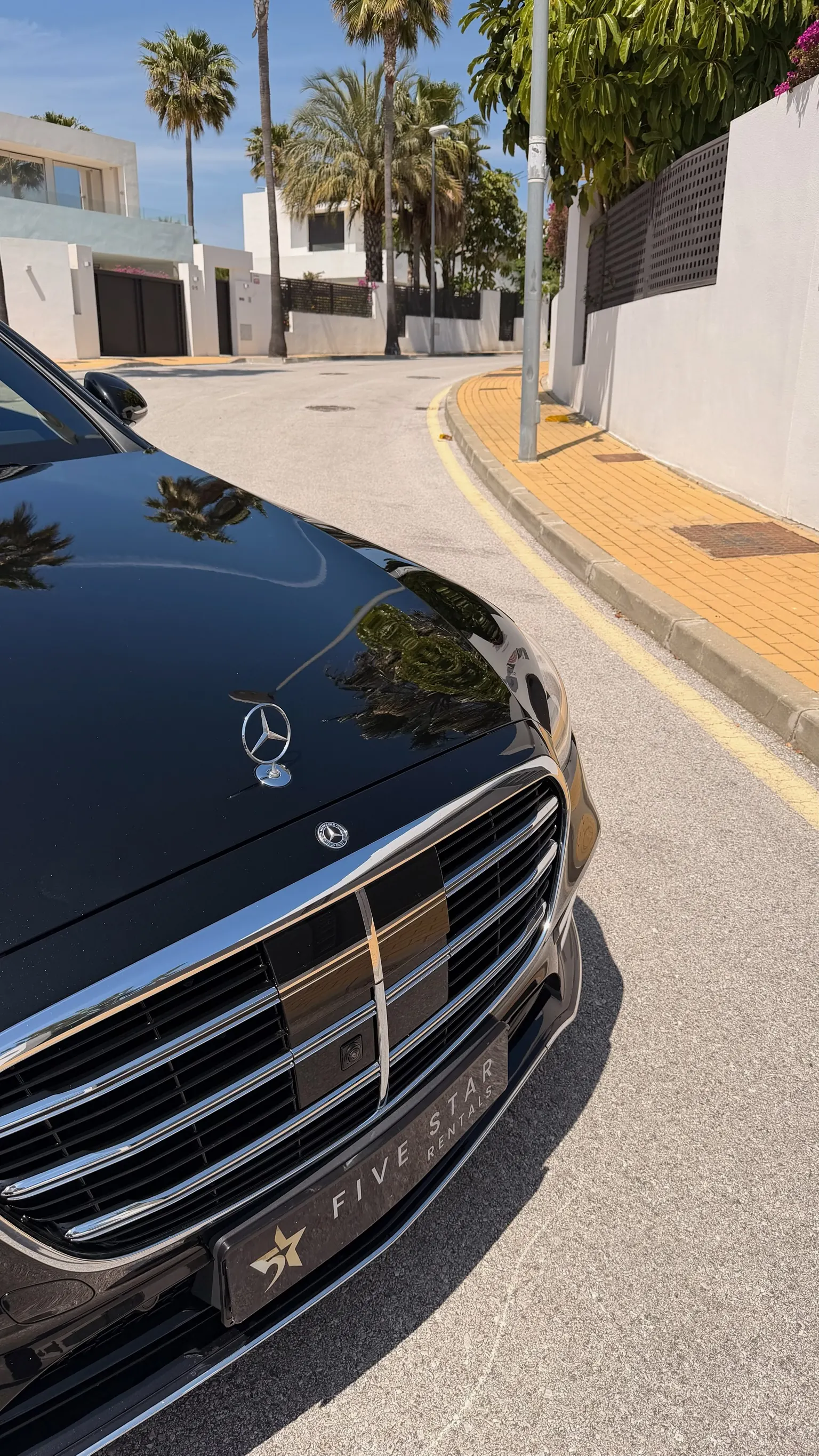 Detalle frontal del Mercedes-Benz S 580 e con estrella central en el capó, parrilla cromada de lamas verticales y matrícula Five Star Rentals