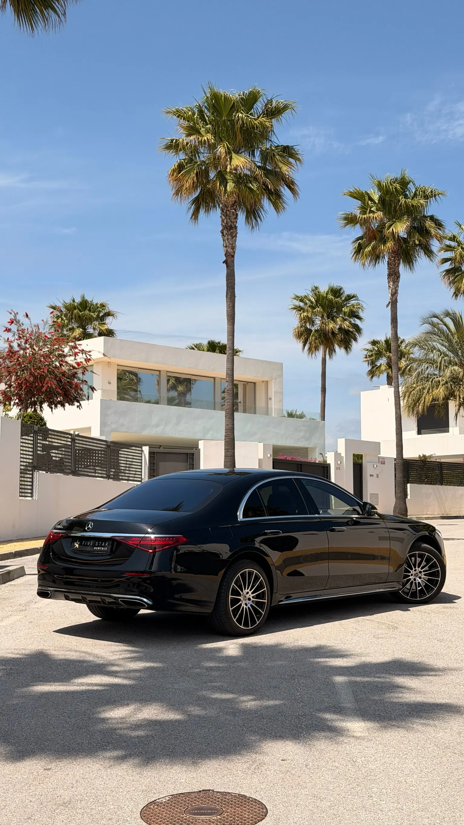 Vista trasera 3/4 del Mercedes-Benz S 580 e con matrícula Five Star Rentals, doble salida de escape integrada y techo panorámico de cristal