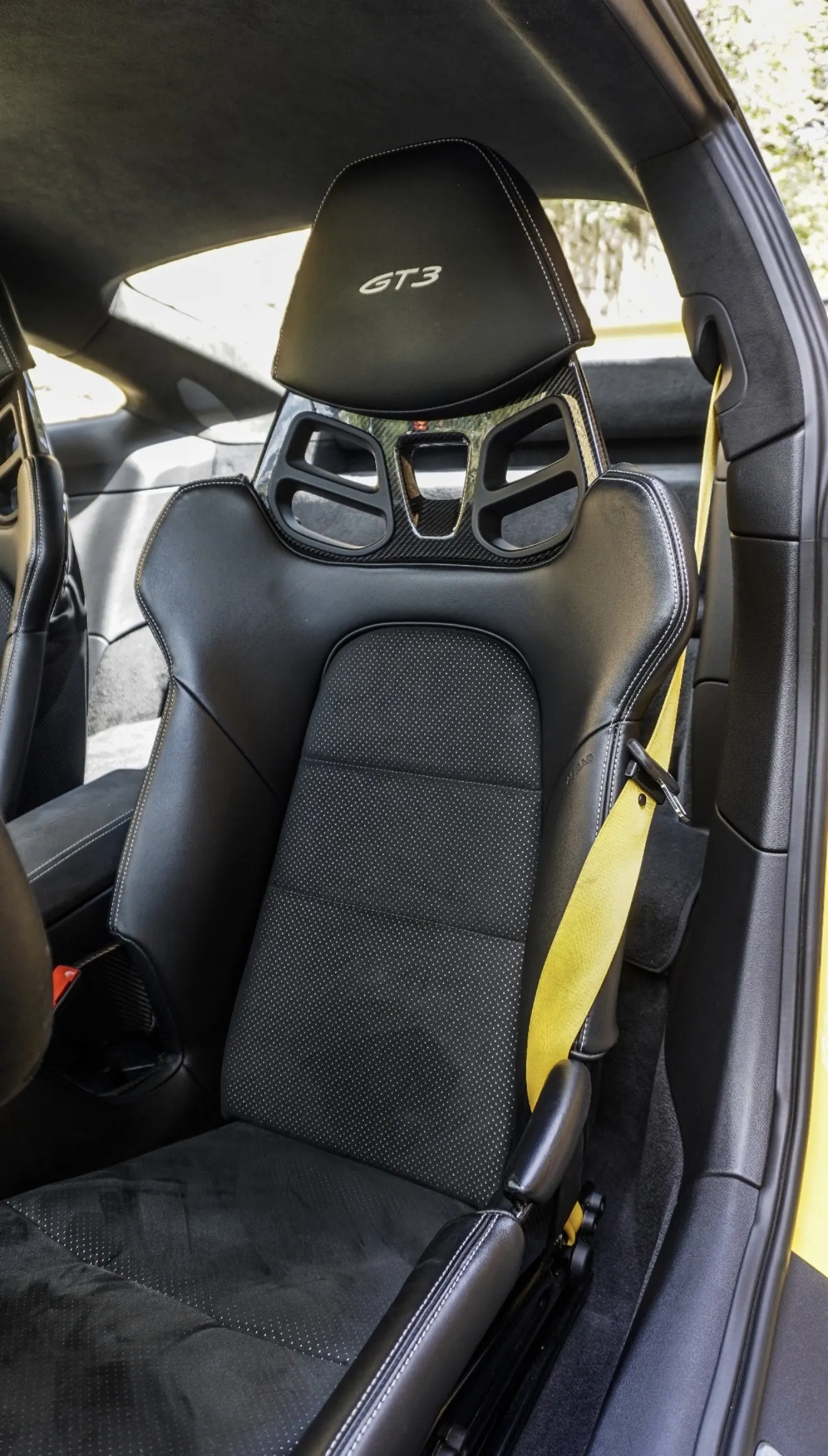 Asiento baquet deportivo del Porsche 911 GT3 992 en cuero negro perforado con logo GT3 bordado en reposacabezas, respaldo en carbono y cinturón amarillo Racing a juego con la carrocería