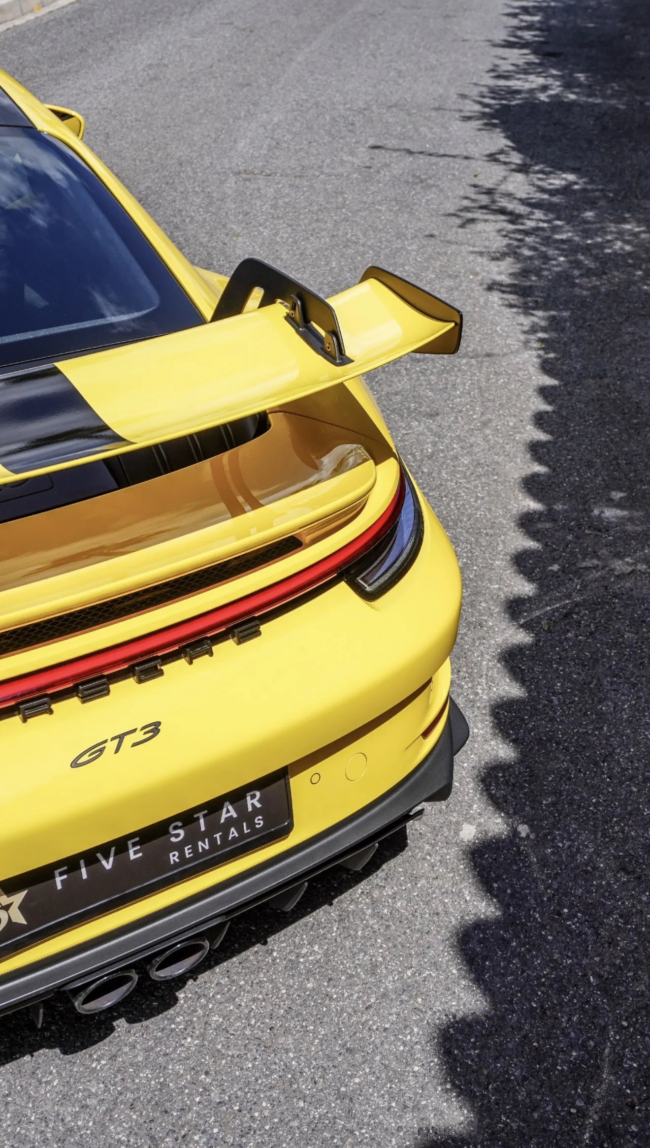 Detalle trasero cenital del Porsche 911 GT3 992 Racing Yellow con alerón col de cisne, barra LED roja, insignia GT3 y doble salida de escape central