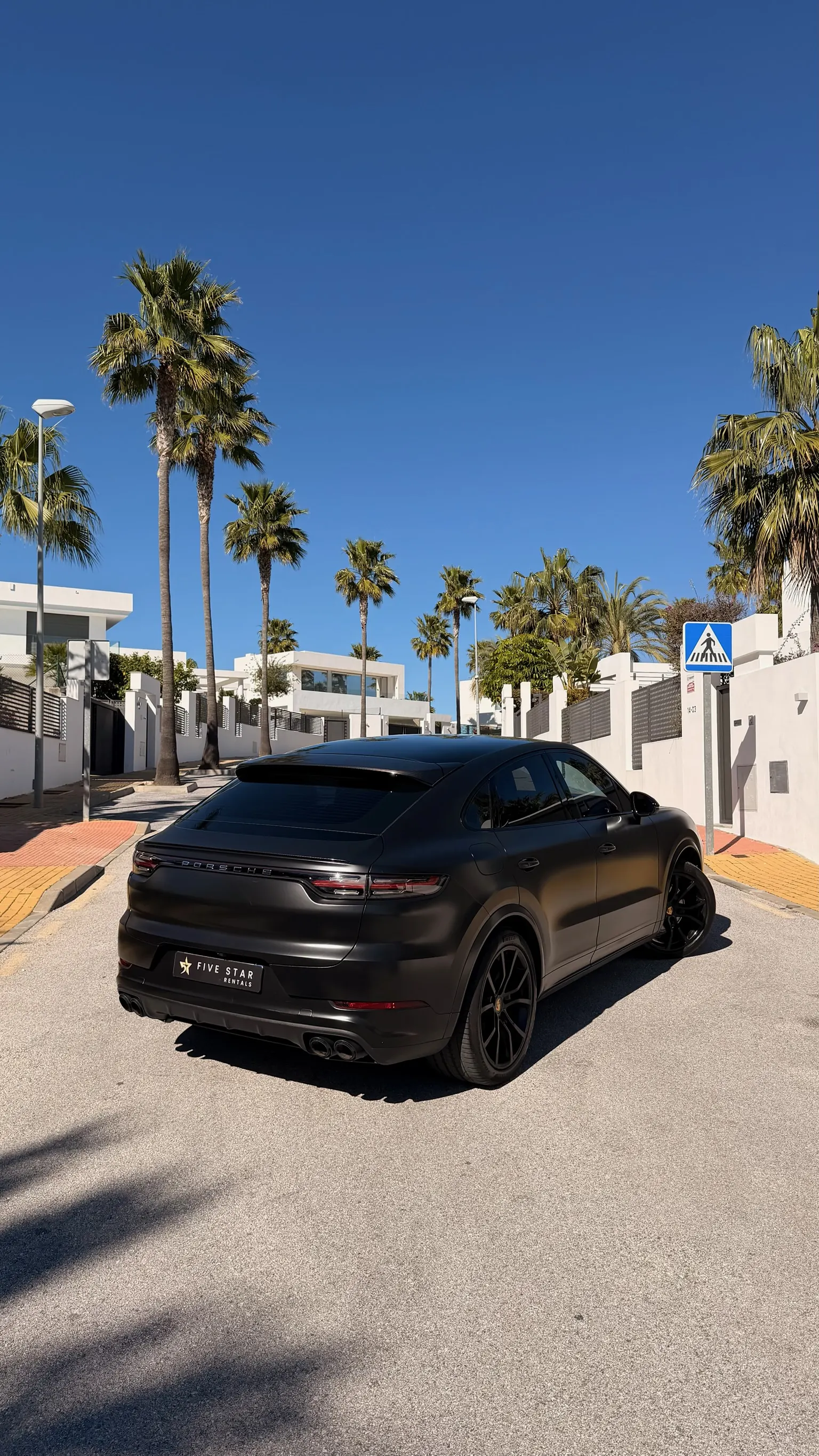 Rear three-quarter view of the matte black Cayenne Coupé E-Hybrid revealing the distinctive aerodynamic sloping roof