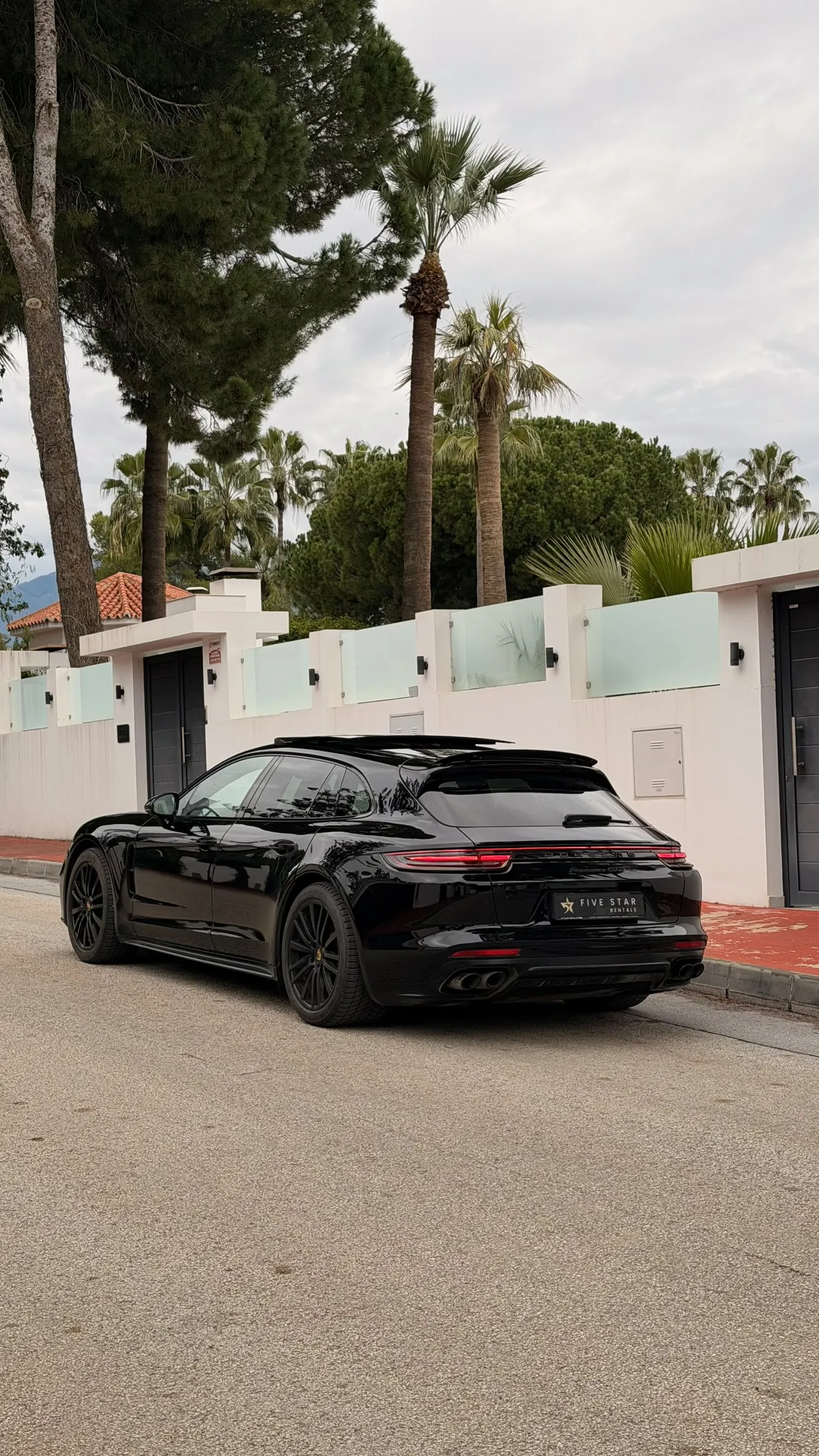 Rear three-quarter view of Panamera GTS Sport Turismo with full LED light bar and Marbella palm trees