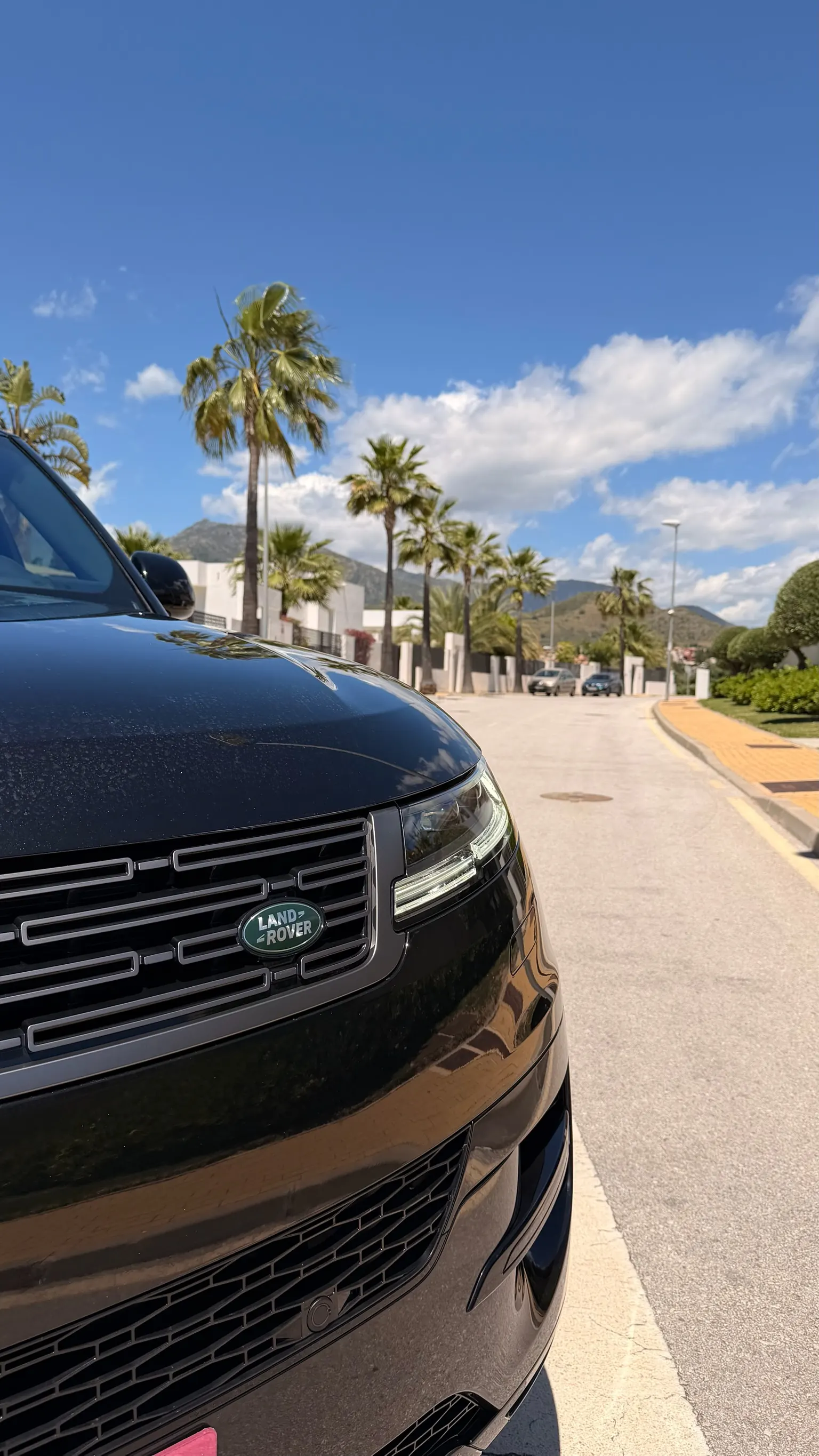 Detalle frontal del Range Rover Sport negro con logo Land Rover ovalado verde y parrilla de lamas horizontales negras