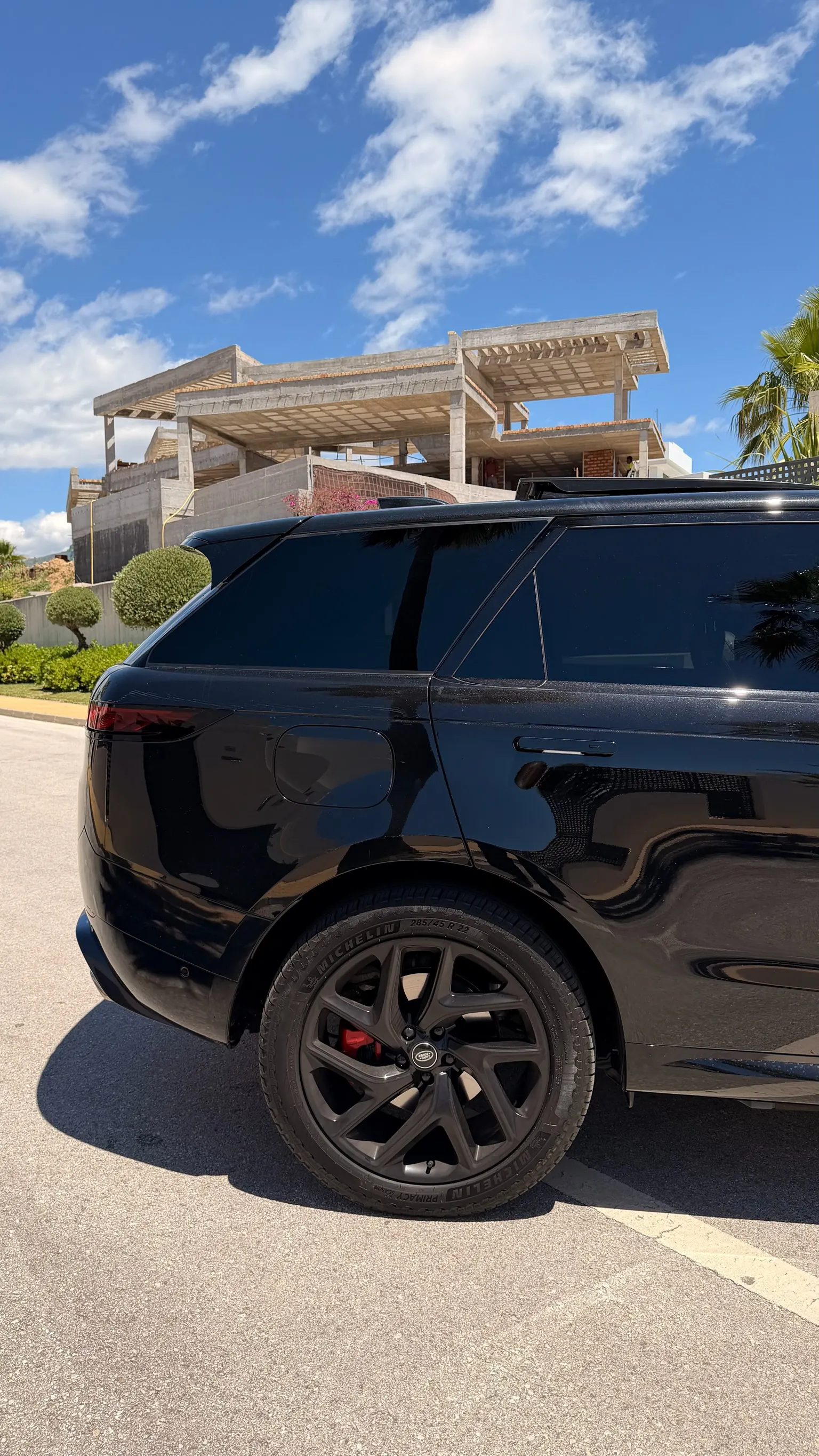 Vista trasera 3/4 del Range Rover Sport P460e con alerón de techo integrado, puerta de carga eléctrica en la aleta y llanta de 22 pulgadas negra