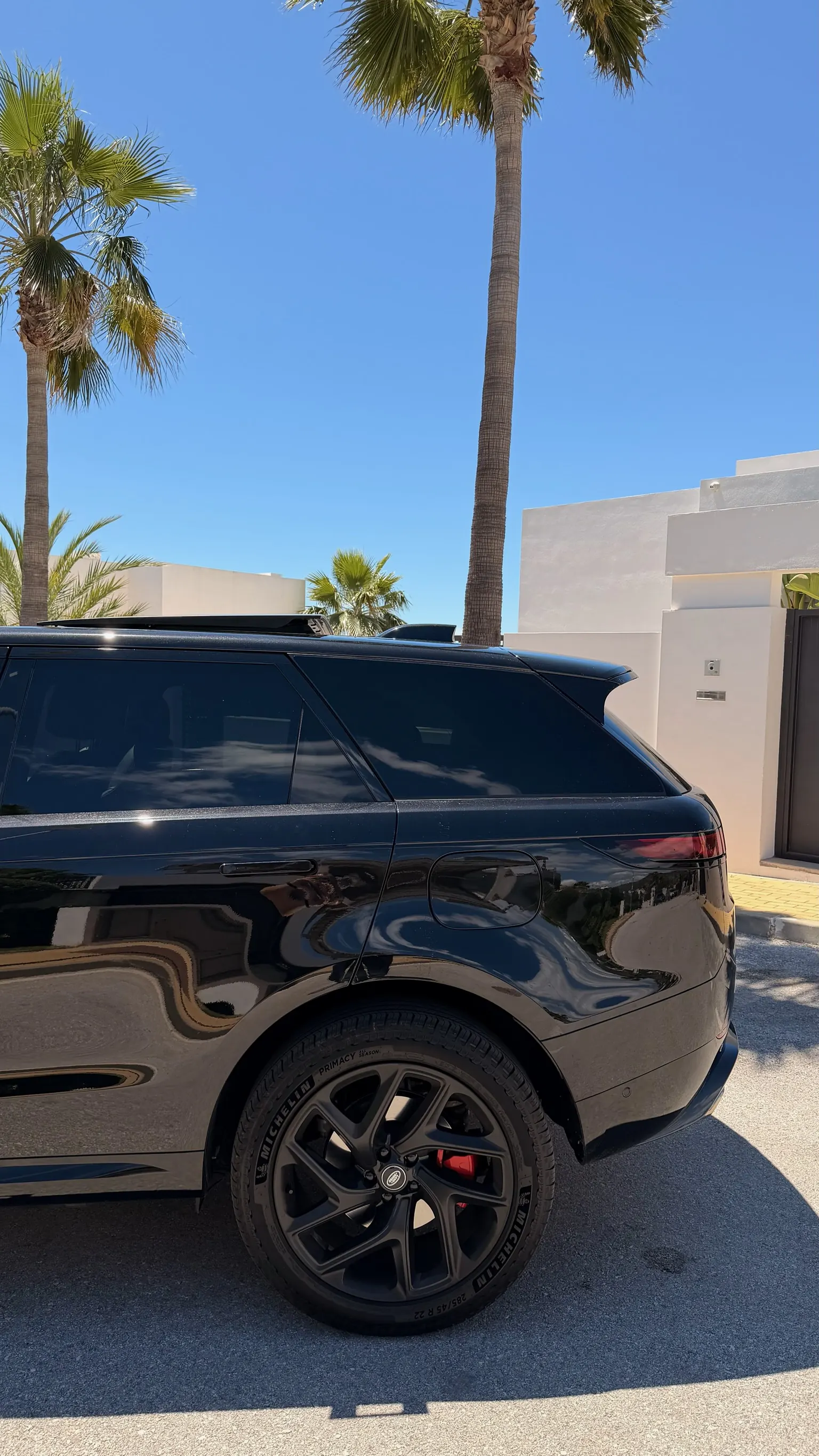 Perfil trasero del Range Rover Sport P460e negro Santorini con línea de techo descendente, llanta de 22 pulgadas y banda LED trasera integrada